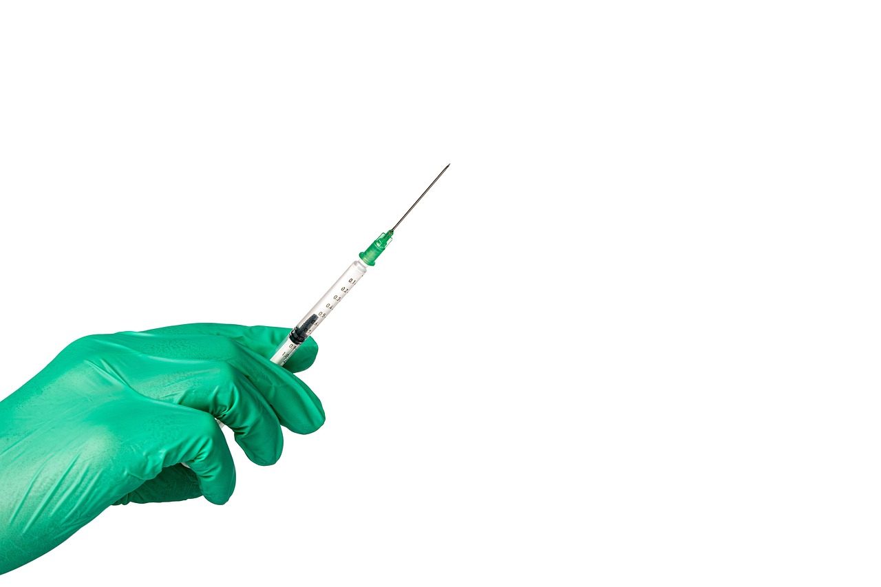 Gloved hand holding a syringe ready for a vaccine injection