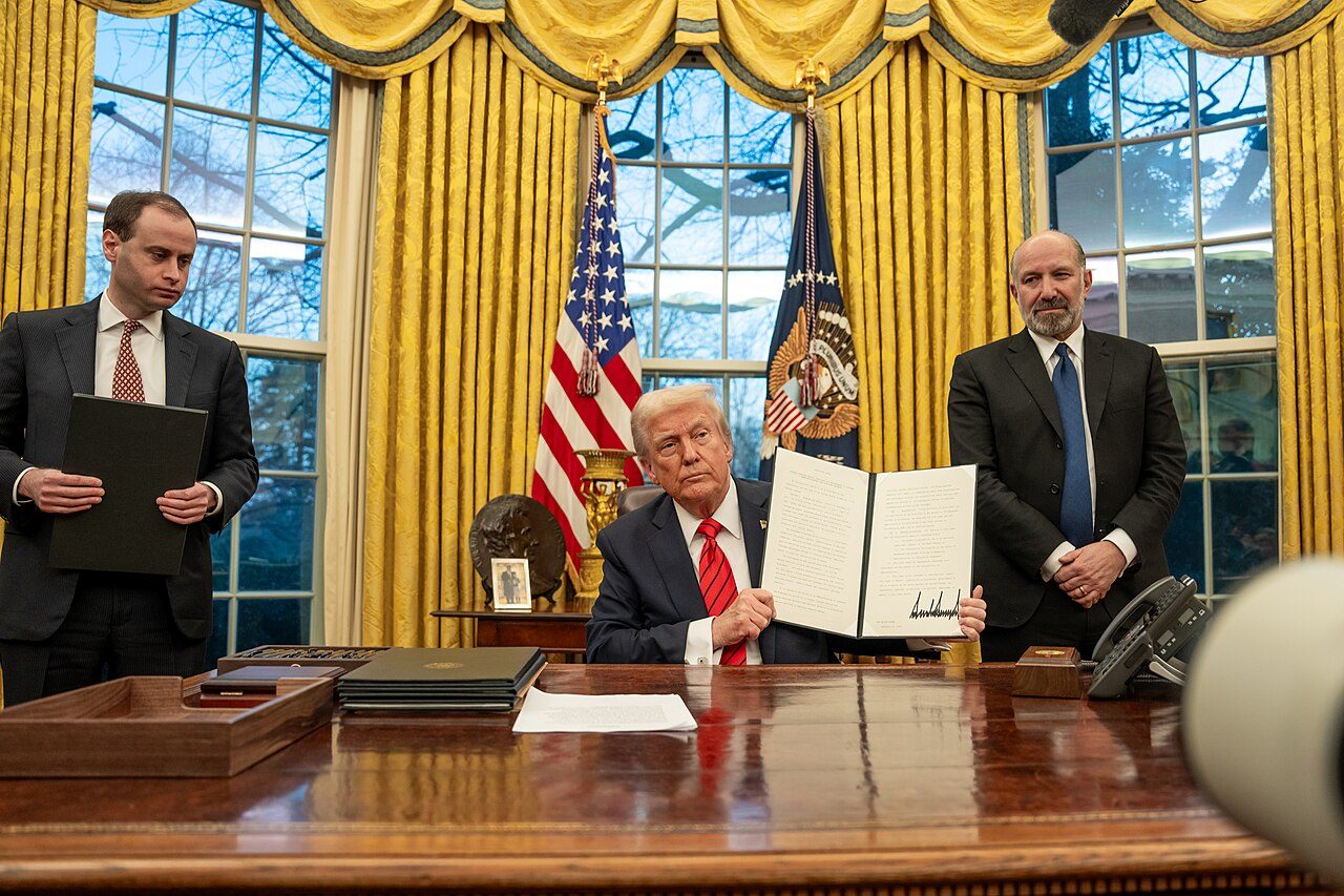 President Donald Trump holds up a signed executive order in the Oval Office in February 2025