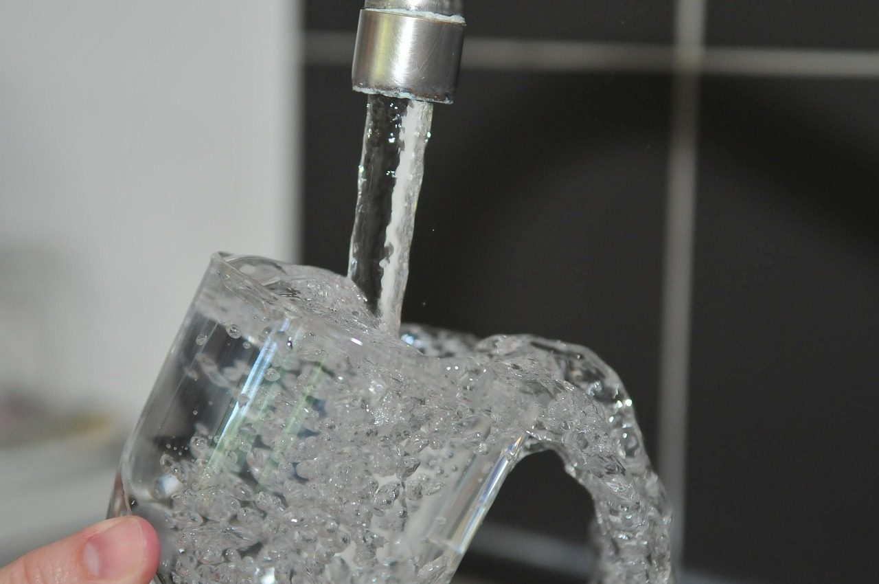 Tap water pouring into a drinking glass from a faucet